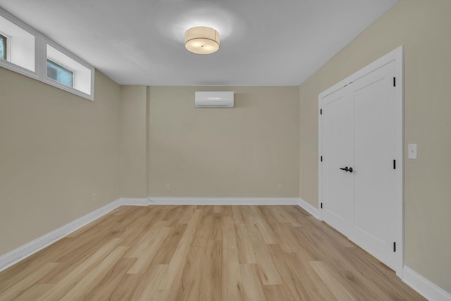 basement featuring light wood-type flooring and a wall mounted air conditioner