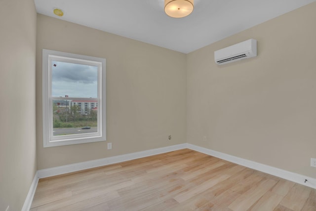 spare room with a wall mounted AC and light hardwood / wood-style flooring