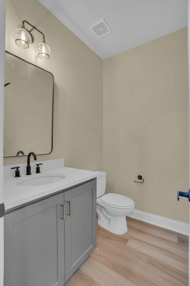 bathroom with toilet, vanity, and hardwood / wood-style floors