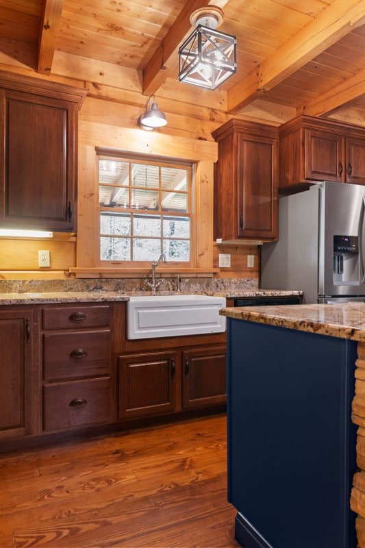 kitchen with sink, decorative light fixtures, stainless steel fridge with ice dispenser, dark hardwood / wood-style flooring, and beam ceiling