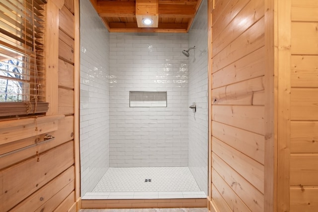 bathroom with a tile shower, wooden ceiling, and wood walls