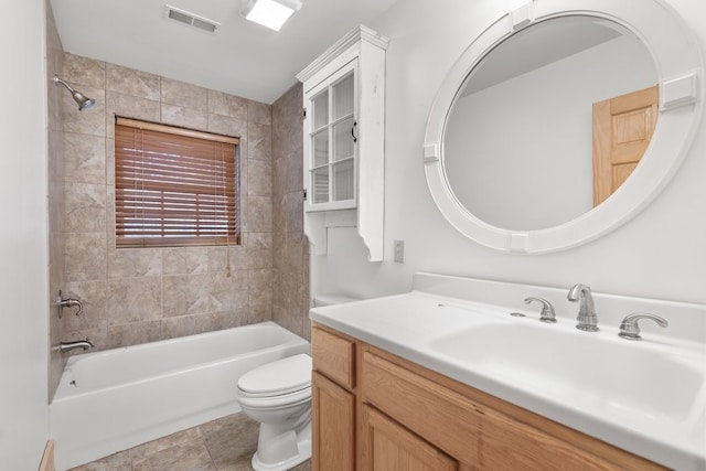 full bathroom with tiled shower / bath, vanity, and toilet