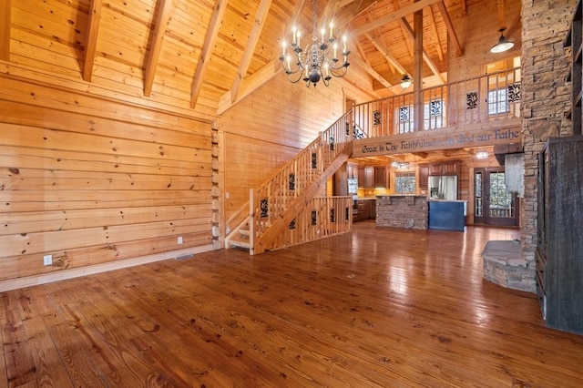 unfurnished living room featuring beam ceiling, a notable chandelier, wood ceiling, and wood walls