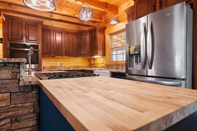 kitchen with pendant lighting, wooden counters, appliances with stainless steel finishes, wooden ceiling, and beamed ceiling