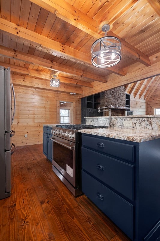 kitchen featuring stainless steel appliances, decorative light fixtures, blue cabinets, and wood walls