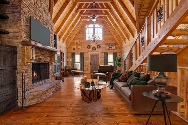 living room featuring wooden walls, wood-type flooring, a fireplace, and high vaulted ceiling