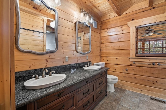 bathroom featuring wooden walls, beamed ceiling, vanity, toilet, and wooden ceiling