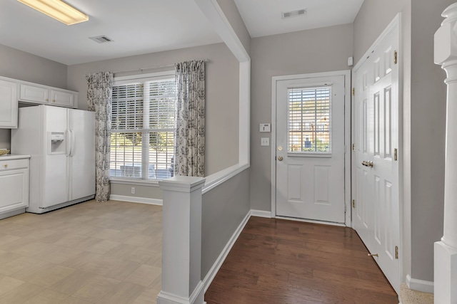 entryway featuring light wood-type flooring and decorative columns