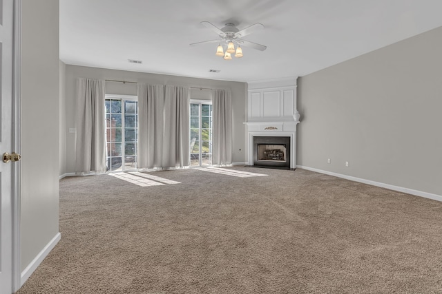 unfurnished living room with ceiling fan, carpet flooring, and a fireplace