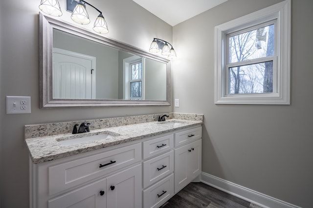 bathroom with a wealth of natural light, double vanity, baseboards, and a sink