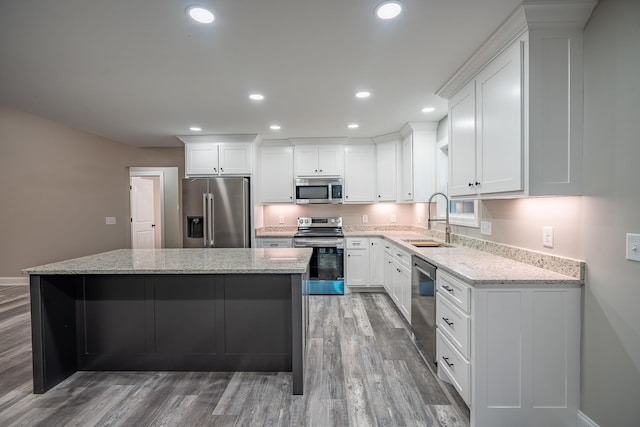 kitchen featuring a center island, recessed lighting, appliances with stainless steel finishes, white cabinetry, and a sink