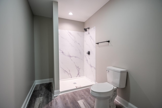 bathroom with a shower stall, toilet, baseboards, and wood finished floors