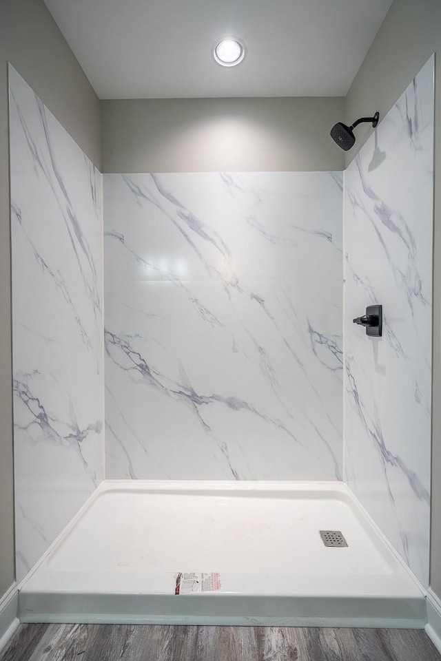 bathroom featuring wood finished floors and a marble finish shower