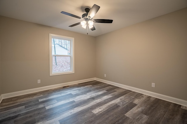 unfurnished room featuring dark wood finished floors, a ceiling fan, and baseboards