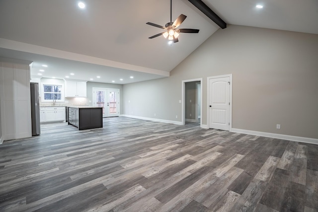 unfurnished living room with ceiling fan, baseboards, beam ceiling, wood finished floors, and high vaulted ceiling