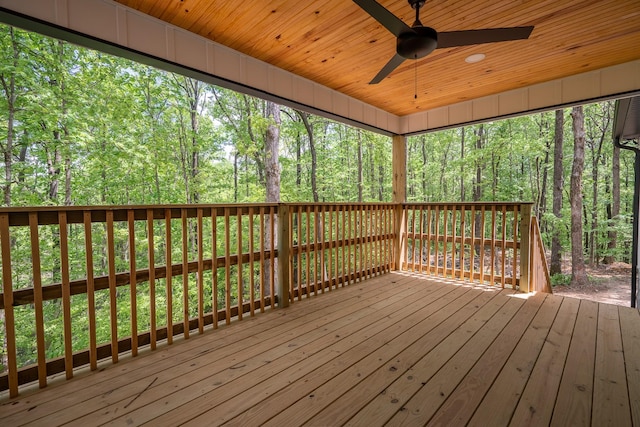 wooden terrace featuring a view of trees and a ceiling fan