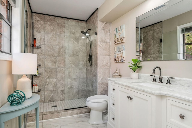 bathroom with a tile shower, toilet, vanity, and marble finish floor