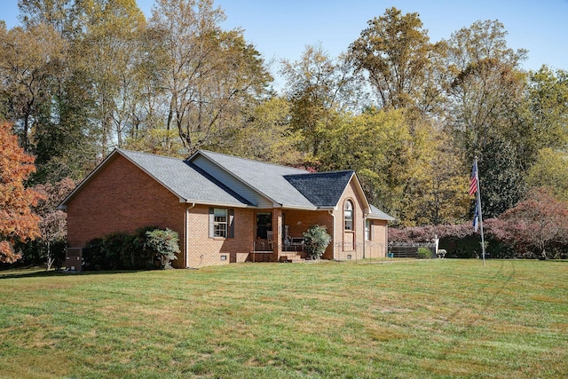 exterior space with covered porch, brick siding, a shingled roof, a yard, and crawl space