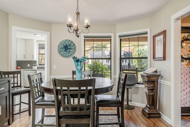 dining area featuring baseboards, a chandelier, and light wood finished floors