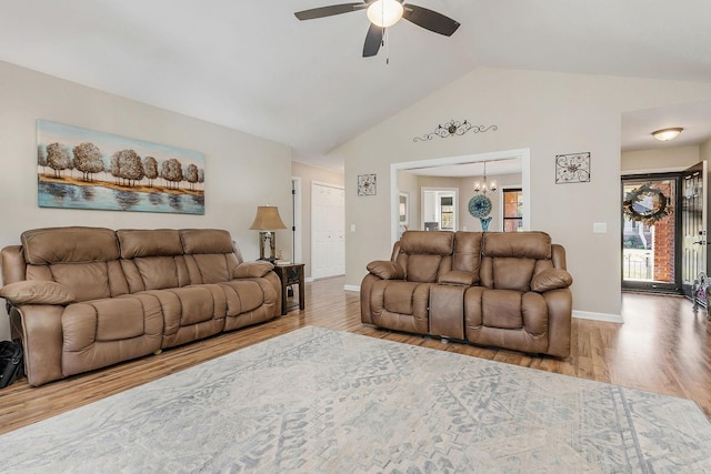 living area with high vaulted ceiling, wood finished floors, baseboards, and ceiling fan with notable chandelier