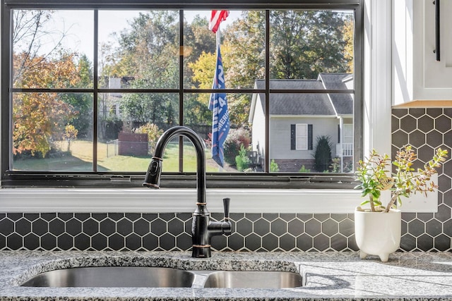 interior details with light stone counters, tasteful backsplash, white cabinetry, and a sink