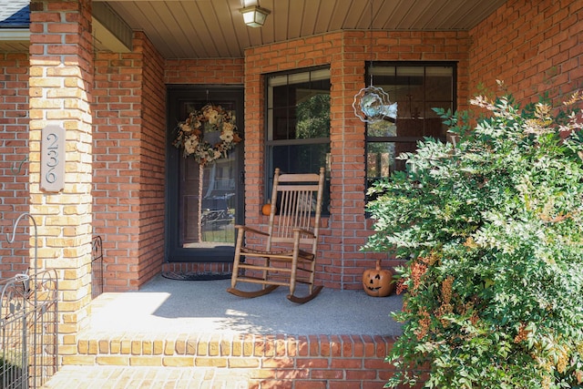 entrance to property featuring brick siding and covered porch
