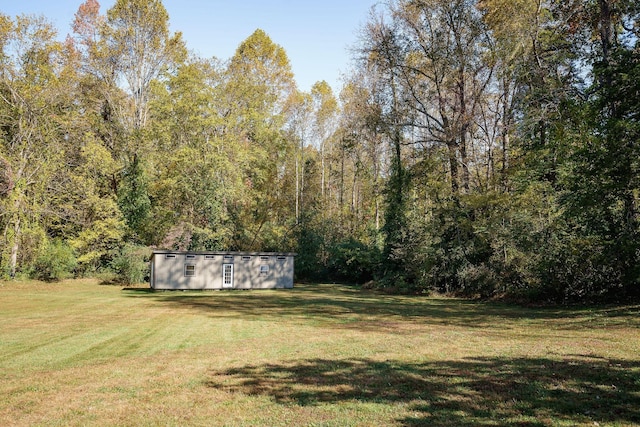 view of yard with an outbuilding, a forest view, and a shed