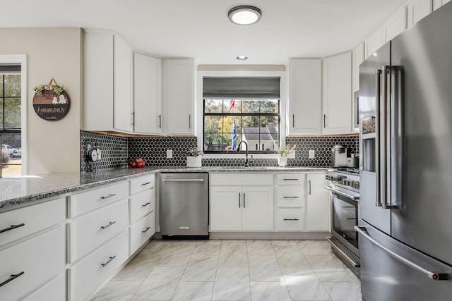 kitchen featuring a healthy amount of sunlight, stone countertops, stainless steel appliances, and a sink