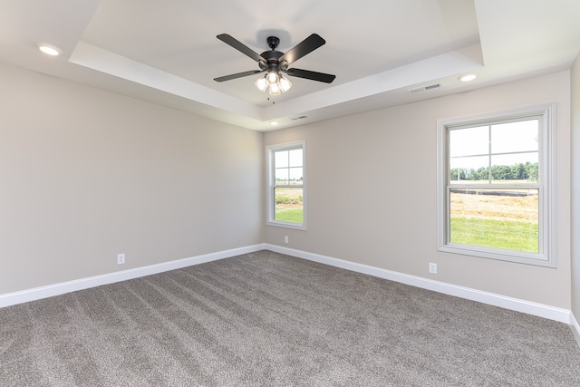 carpeted spare room featuring a raised ceiling and ceiling fan