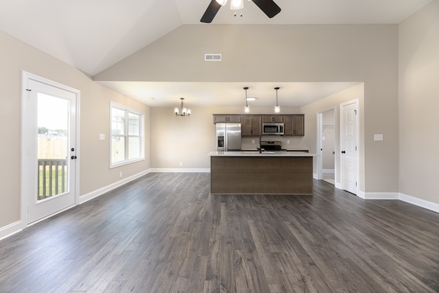 kitchen featuring vaulted ceiling, appliances with stainless steel finishes, dark hardwood / wood-style floors, hanging light fixtures, and a center island with sink