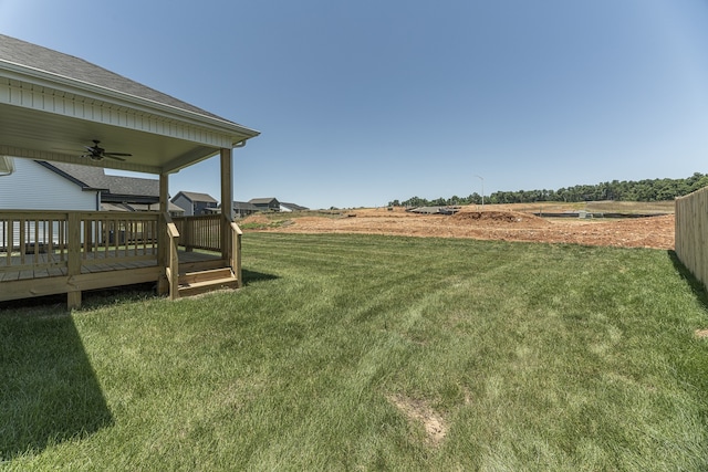 view of yard with a wooden deck, ceiling fan, and a rural view