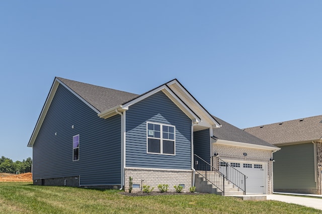 view of front of property with brick siding, roof with shingles, a lawn, a garage, and driveway