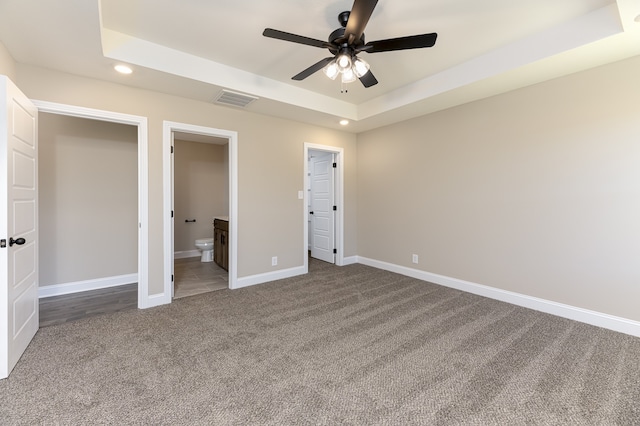 unfurnished bedroom with visible vents, a tray ceiling, recessed lighting, carpet floors, and baseboards