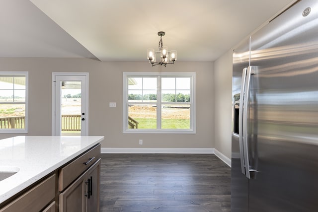 kitchen with light stone counters, dark wood-style floors, stainless steel fridge, and baseboards