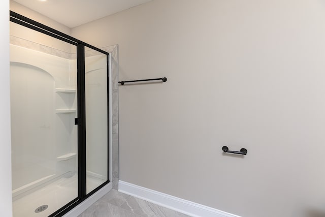 bathroom featuring baseboards, marble finish floor, and a stall shower