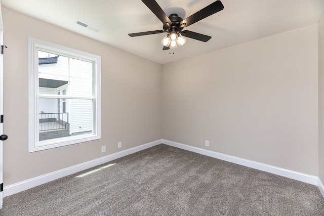 unfurnished room featuring visible vents, dark carpet, baseboards, and ceiling fan