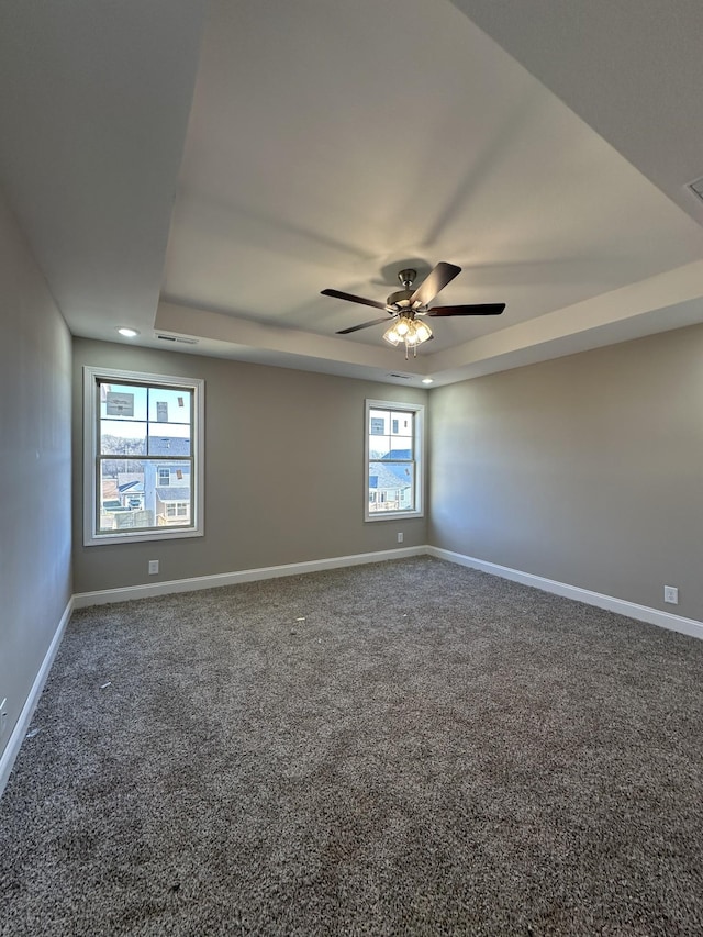 carpeted empty room featuring visible vents, baseboards, a tray ceiling, recessed lighting, and a ceiling fan