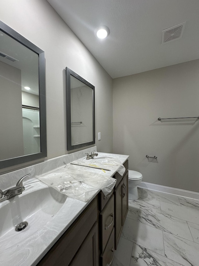 bathroom featuring visible vents, baseboards, double vanity, marble finish floor, and a sink