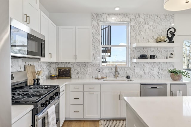 kitchen featuring white cabinets, stainless steel appliances, tasteful backsplash, and sink