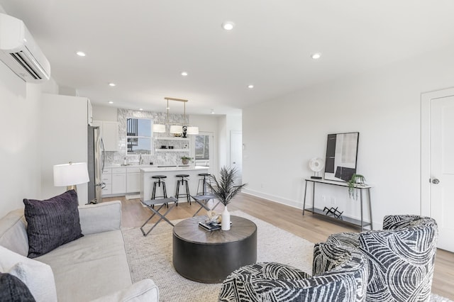 living room with a wall mounted air conditioner and light hardwood / wood-style flooring