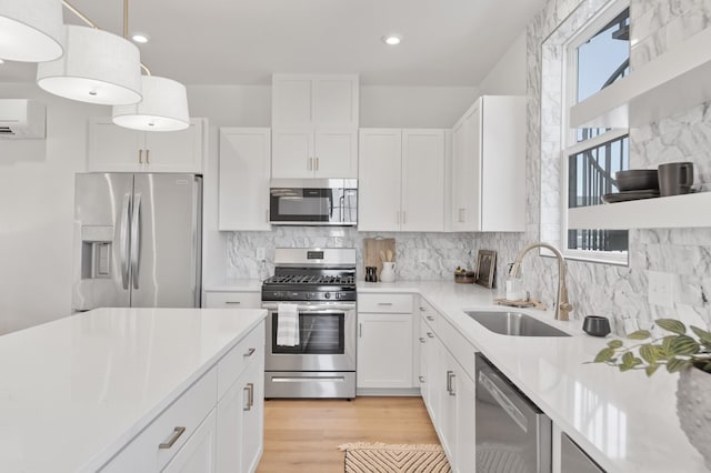 kitchen featuring pendant lighting, sink, appliances with stainless steel finishes, white cabinetry, and an AC wall unit