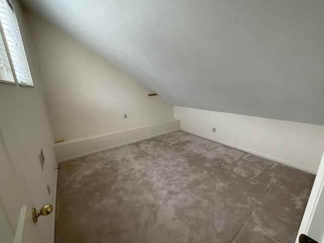 additional living space with lofted ceiling and a textured ceiling