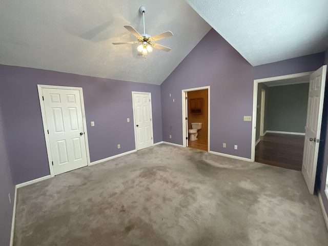 unfurnished bedroom featuring ceiling fan, carpet flooring, vaulted ceiling, and ensuite bath