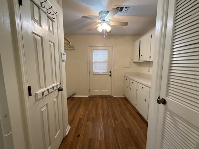 laundry area featuring ceiling fan, dark wood-type flooring, and a textured ceiling