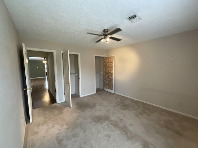 unfurnished bedroom featuring carpet, a textured ceiling, and ceiling fan