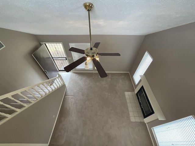 unfurnished living room featuring ceiling fan, carpet floors, high vaulted ceiling, and a textured ceiling