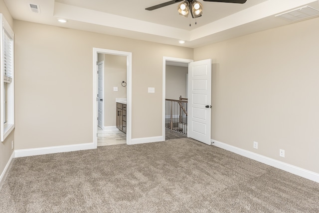 unfurnished bedroom featuring carpet flooring, ceiling fan, and a tray ceiling