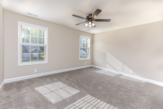 empty room with carpet flooring, visible vents, baseboards, and ceiling fan