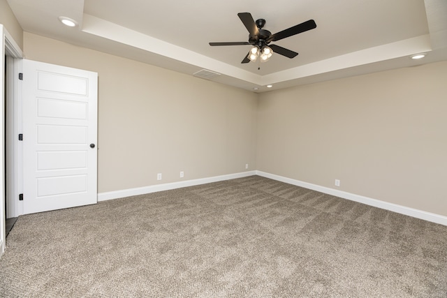 spare room with ceiling fan, a raised ceiling, and carpet floors