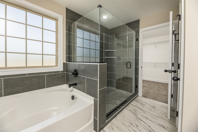 bathroom featuring a bath, a shower stall, a spacious closet, and marble finish floor